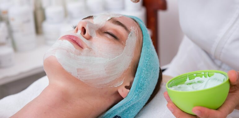 woman lying on blue towel with white cream on face