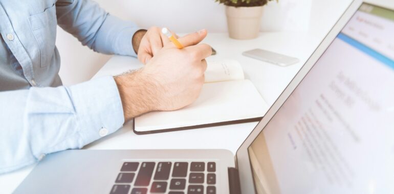 person writing on white notebook