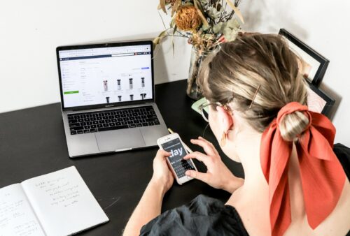 woman in orange shirt using iphone