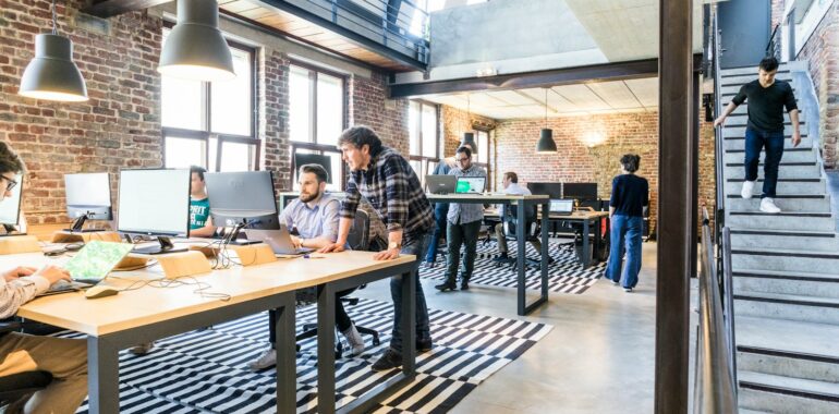 man standing beside another sitting man using computer