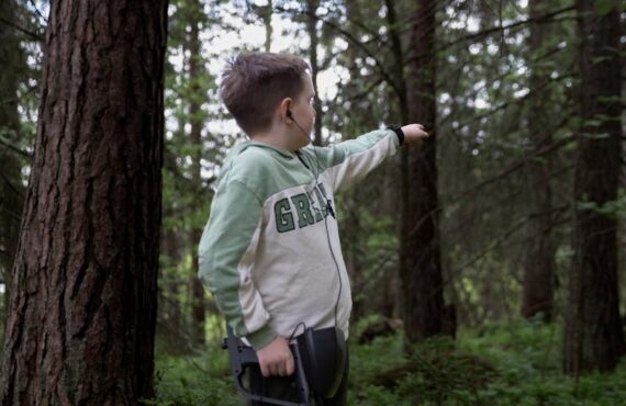 Boy with Metal Detector in Forest